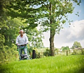 Man mowing lawn wearing ear protectors