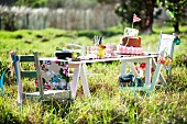 Tiered cake with flag and crockery for child's birthday party on simple wooden table in meadow