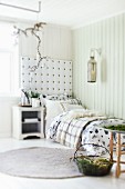 Cushions and blankets on comfortable bed with upholstered headboard panel; festive Advent arrangement of organic, natural items
