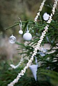 White Christmas decorations and popcorn garland on fir tree outside