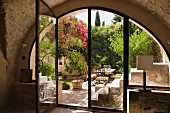 View into sunny Mediterranean courtyard through semi-circular glass wall