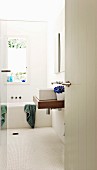 View into white bathroom with washstand and bathtub below window