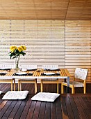 Überdachte Terrasse eines Holzhauses mit gedecktem Tisch und Holzbank