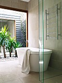 Free-standing bathtub in front of panoramic window with view of yuccas in gravel courtyard