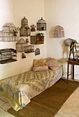 Vintage birdcages mounted on wall above couch in corner of simple room