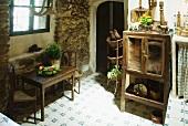 Simple kitchen table and chairs below window and old kitchen cupboard in dining room of farm house