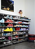 Collection of trainers in open, metal shoe rack next to small, retro upholstered stool