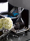 Red wine and vase of hydrangeas on side table in living room