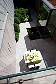 View down onto set table on sunny terrace in courtyard of contemporary house