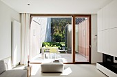 View from designer living room through French windows of outdoor furniture in patio-style courtyard