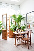 Breakfast table and house plants in front of doors leading to garden