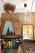 Enormous letter A leaning against brick wall behind Eames chair and pommel horse