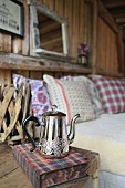 Silver teapot and book on rustic bedside table next to bed