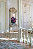 Balustrade, painted wooden column and tall doors with gilt ornamentation in foyer of stately home