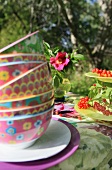 Stack of colourful bowls on summery table in garden