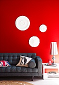 Stucco rosettes on a red wall above grey sofa