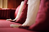 Ausschnitt bordeauxroter und weisser Kissen mit Quasten auf einem rotem Sofa (Schloss Schauenstein)