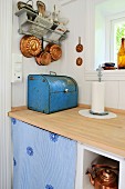 Vintage-Brotkasten und Koch-und Backutensilien aus Kupfer in renovierter Küche mit heller Arbeitsplatte aus Holz und weissen Holzwänden