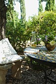 Wine glass and cushions on antique stone bench and book on tiled table