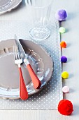 Place mat decorated with colourful pompoms
