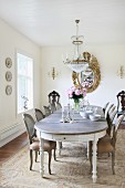 Simple Baroque furniture, glass chandelier and gilt-framed mirror in grand dining room