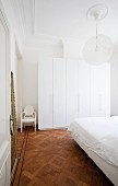 Stuckdecke und Parkett mit Intarsienstreifen in minimalistischem Schlafzimmer mit schlichter, weisser Möblierung
