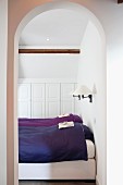 Einzelbetten mit blauer und violetter Bettwäsche in weißem Schlafzimmer mit Einbauschrank unter der Dachschräge