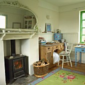 Interior with half-height wooden panelling, various old, wooden furnishings and ornate mirror above log burner in fireplace