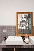 Toilet paper in mouth of crocodile figurine on tiled washstand; portrait drawn on mirror in old gilt frame