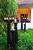 Lit candles on black, floor-standing candlesticks in garden