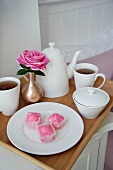 Tea service, petit fours and pink rose on a tray