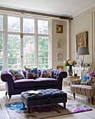Purple sofa, ottoman and armchair in front of living room window