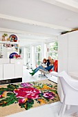Family in white, open-plan interior with large-format rose pattern on kilim rug