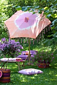 Relax on exotic furnishings in summer garden - batik parasol with bamboo base and comfortable cushions on lawn