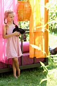 Summer idyll - little girl holding black cockerel in front of couch in Oriental colours
