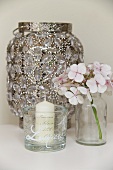 Candle in glass with pattern of lettering, hydrangea flower and antique lantern decorated with crystals
