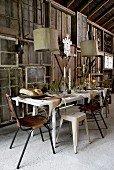 Festively set table below pendant lamps in front of DIY wooden wall made from window frames and wooden panels in barn-like room