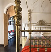Double bed with Oriental brass frame next to open door showing chairs against wall in hallway beyond