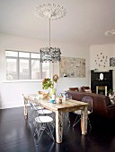 Wooden table and retro, wire mesh chairs below pendant lamp suspended from ceiling rose