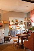 Eclectic country-style interior with rustic wooden furniture and soft, shabby-chic colour scheme in dining room with view into kitchen