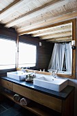 Modern washstand with twin basins below framed mirror in bathroom with rustic, modern ambiance
