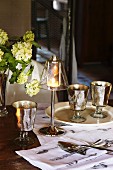 Elegant candle lantern on lamp base next to vintage wine glasses on table