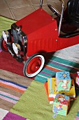 Angled view of vintage-style child's car and toys on striped rug