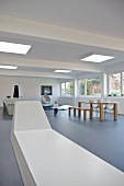 Lange Sitzbank in futuristischem Designerstil und Essplatz in offenem, minimalistischem Wohnzimmer