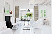 Various chairs around rustic table in front of terrace doors with interior shutters