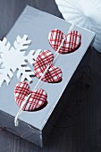 Wrapped Christmas present decorated with red and white checked fabric hearts and wooden snowflake