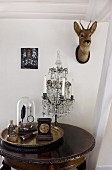Collection of antique objet on brass tray and candelabra on side table; deer's head on wall