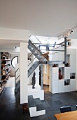 Verschachtelte Galerieebenen in einem Wohnraum mit puristischer, offener Metallgittertreppe