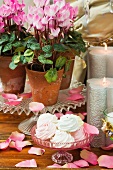 Baisergebäck, silberne Kerzen und Cyclamen in Blumentöpfen