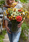 Woman carrying summer bouquet of dahlias, alstroemeria, chamomile and rudbeckia